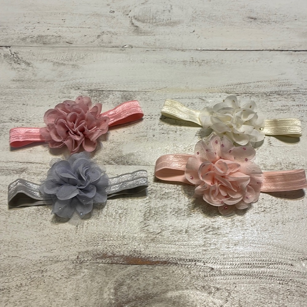 Lot of four baby girl headbands with sparkly flowers, cream, gray and two pinks.